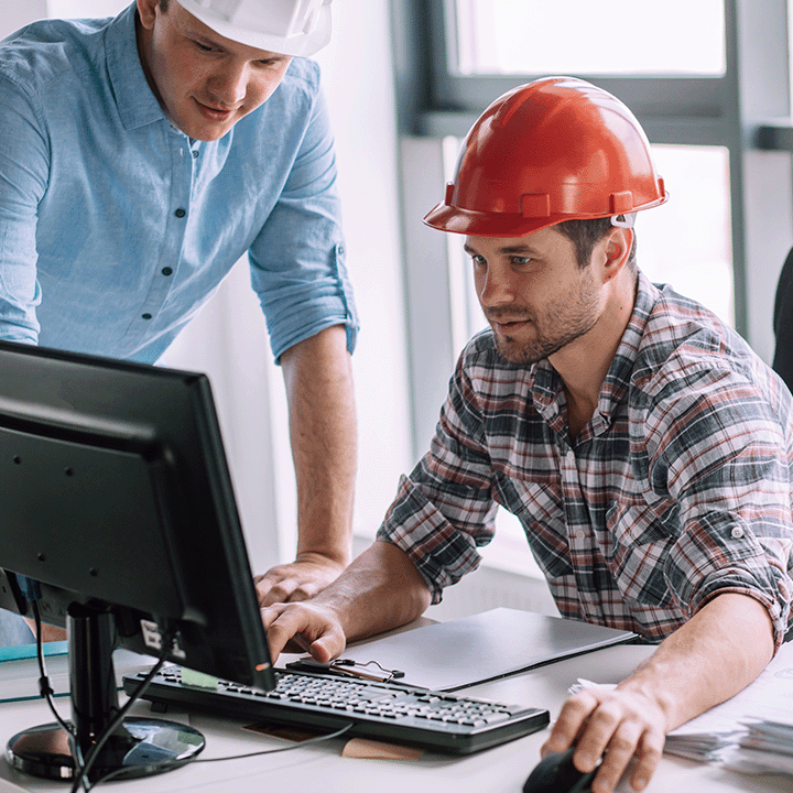 Builder in a red hard hat using a computer