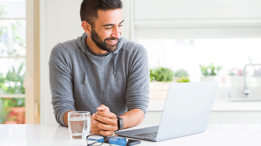 Picture of a man on his laptop with a glass of water 