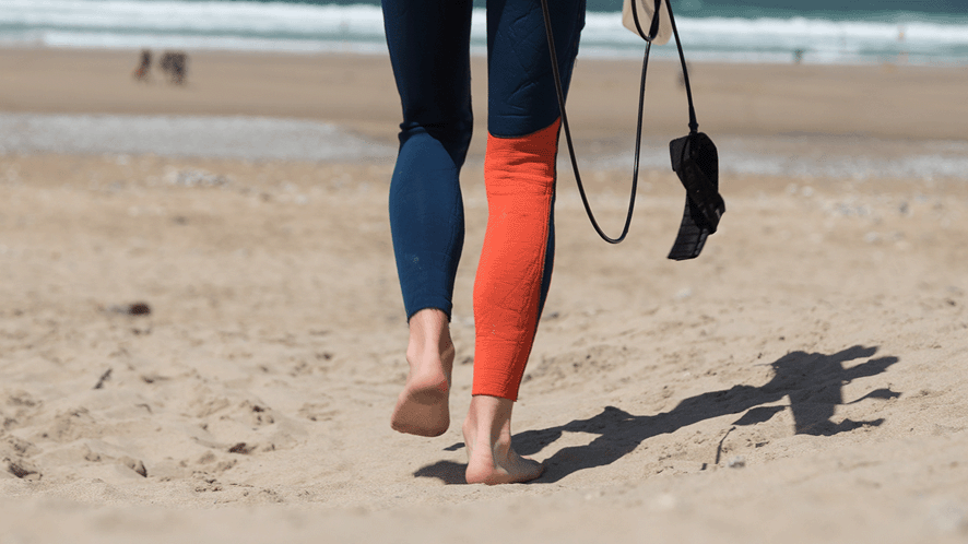 Surfers legs walking on beach