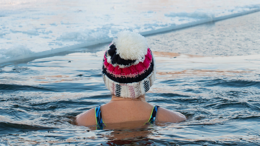 Lady in a bobble hat swimming in icy water