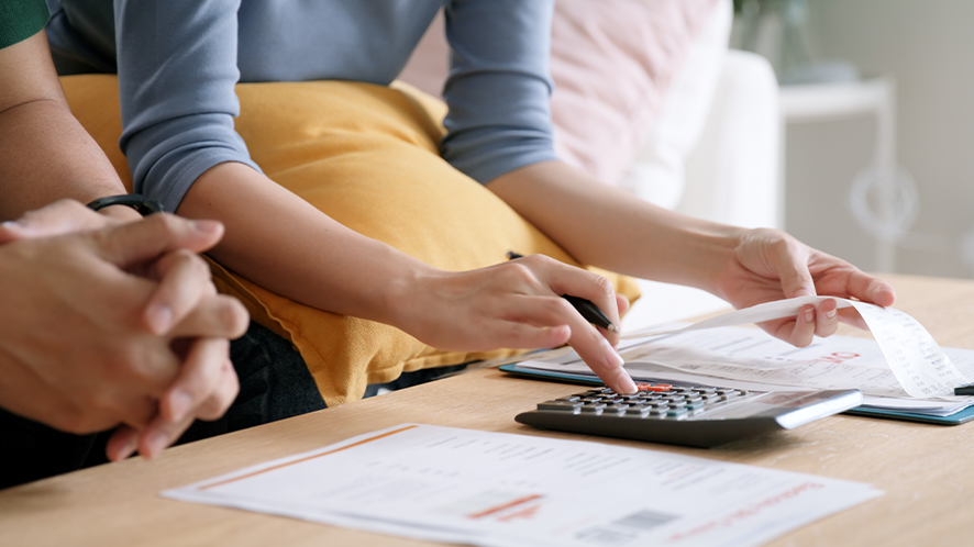 Lady looking at bills and using a calculator