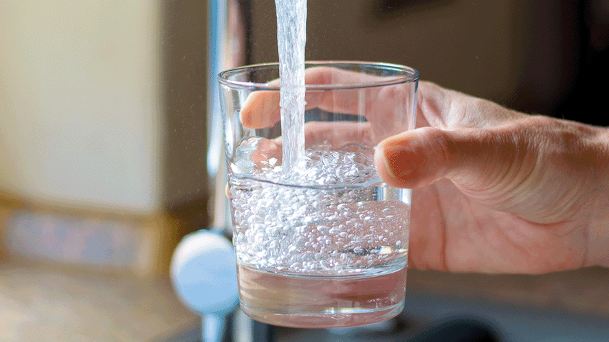 Glass under tap being filled with water