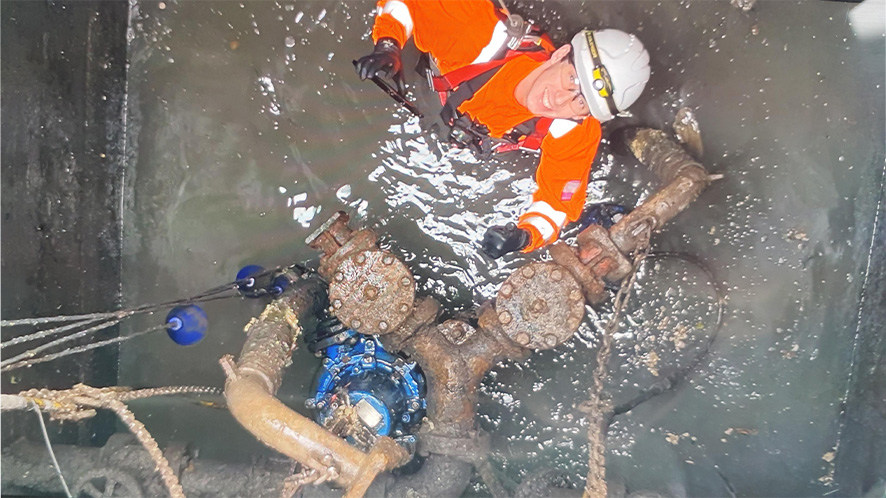 man in blocked up pump chamber waist-deep in water