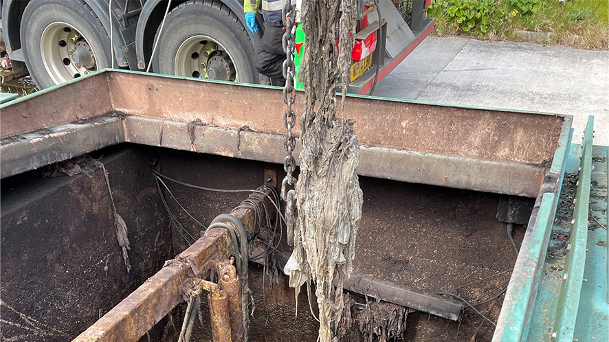 Picture of a large clump of wipes being lifted out of a drain with a crane